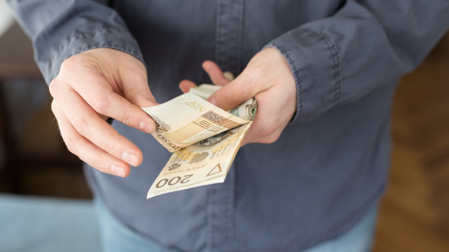 Człowiek liczący pieniądze o nominale 200 złotych.