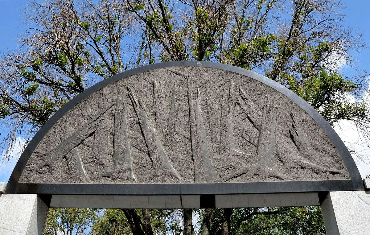 Granitowy blok nad wejściem z symbolem strzaskanego lasu.