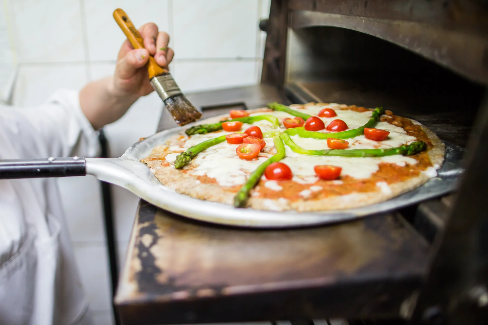 Pizza orkiszowa ze szparagami, pomidorkami koktajlowymi, serem i sosem pomidorowym przed...