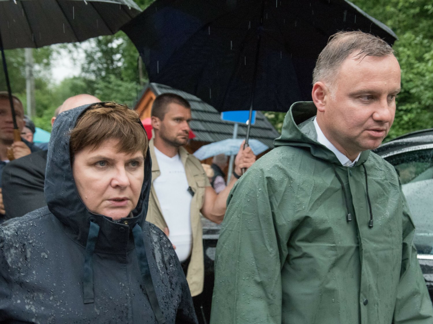 Na zdjęciu prezydent Andrzej Duda i była premier Beata Szydło w strojach przeciwdeszczowych na miejscu powodzi w Polsce.