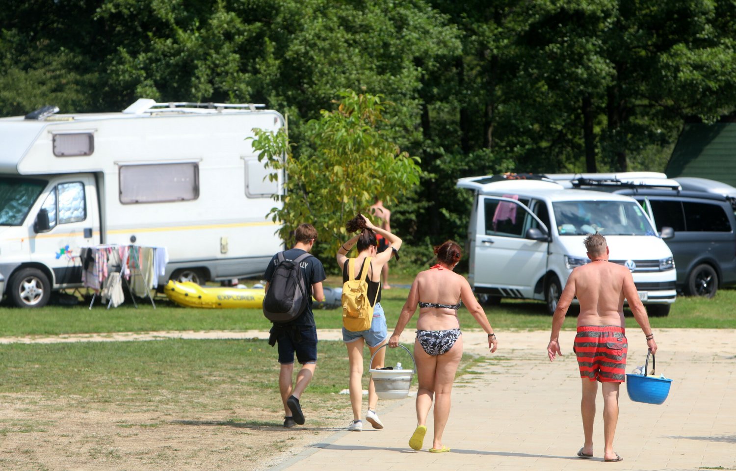 Kemping w Chorwacji. Na zdjęciu ludzie idący z plaży w kierunku kamperów i namiotów.