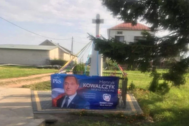 Baner ministra Kowalczyka zawieszono na płocie przydrożnej kapliczki.