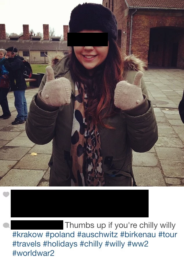 Kciuki w górę na tle obozu koncentracyjnego Auschwitz-Birkenau.