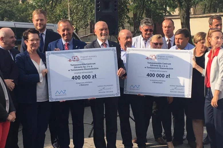 Antoni Macierewicz trzyma czek, a wiceminister zdrowia stoi w drugim rzędzie.