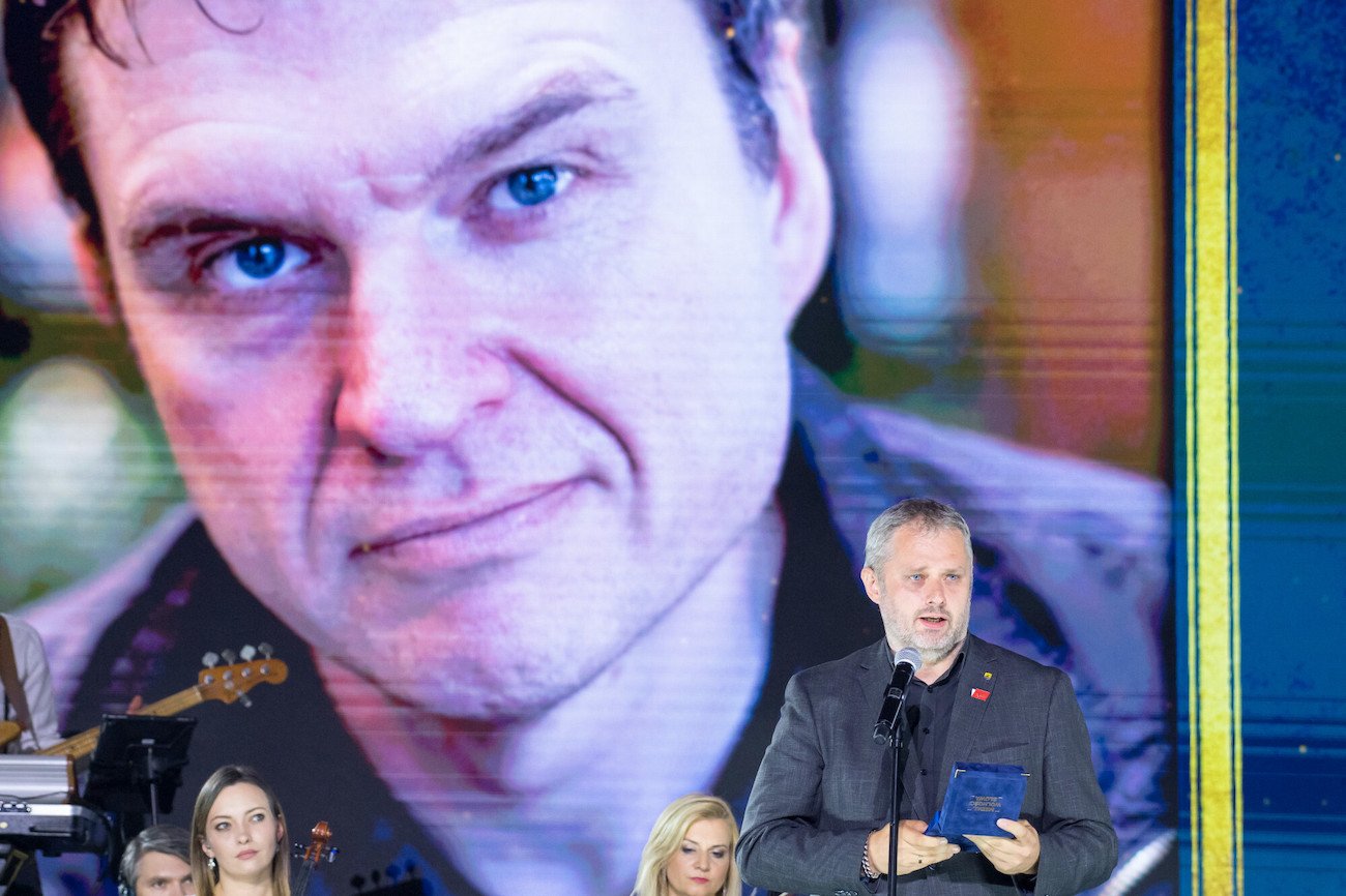 Bartosz Wieliński odbierający Medal Wolności w imieniu uwięzionego na Białorusi dziennikarza "Gazety Wyborczej" Andrzeja Poczobuta (wizerunek w tle).