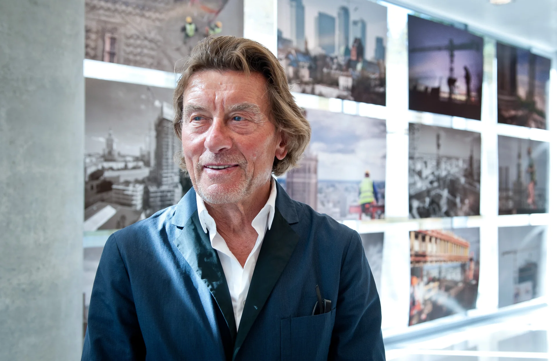 Helmut Jahn na tle galerii fotografii z budowy wieżowca, w lobby budynku