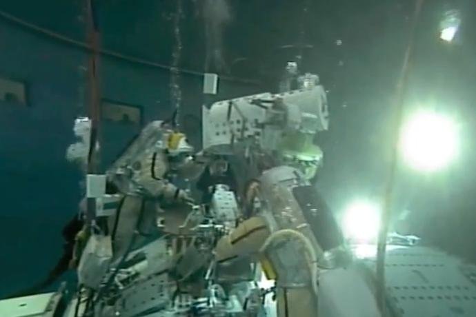 Kosmonauci trenują  przyczepianie kamer na podwodnym modelu stacji kosmicznej.