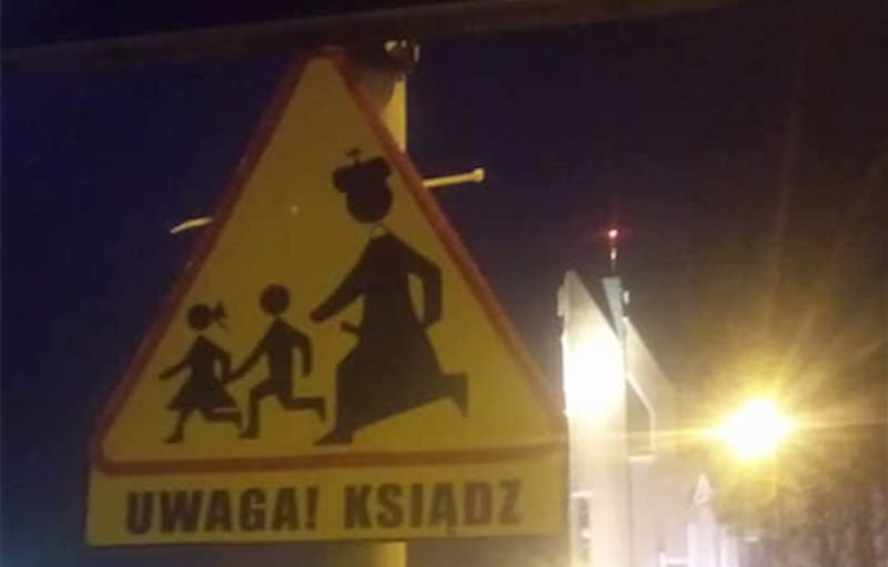 Toruń: Ksiądz biegnący za dziećmi na znaku drogowym obok kościoła.