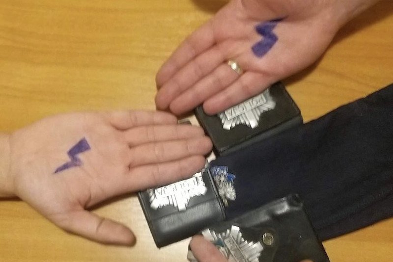 Zdjęcie z błyskawicami na dłoniach. Widać też policyjne odznaki.