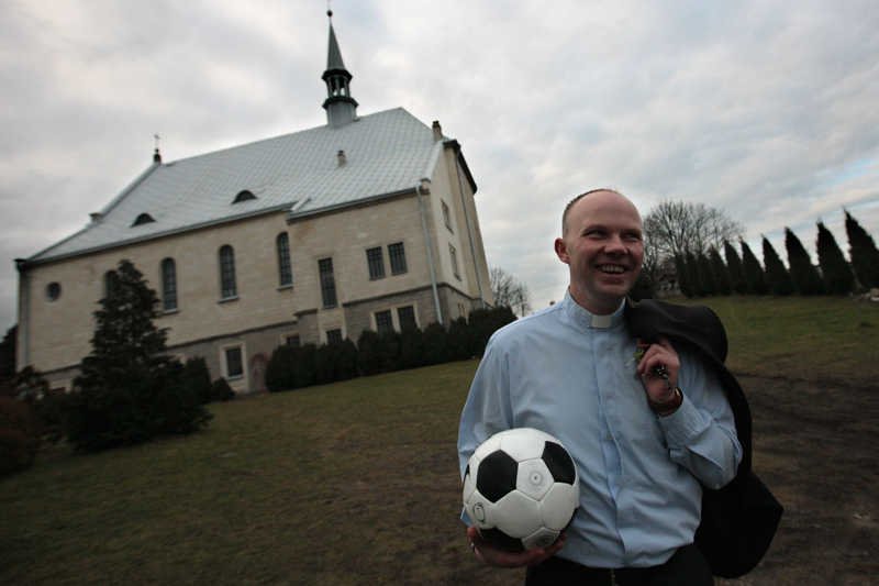 Ksiądz Piotr, z piłką i uśmiechem na twarzy.