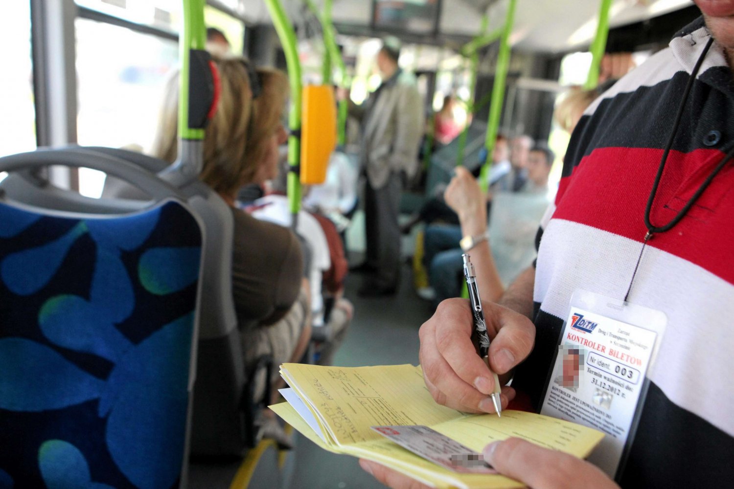 Kontroler biletów, popularnie zwany "kanarem", wystawia mandat.