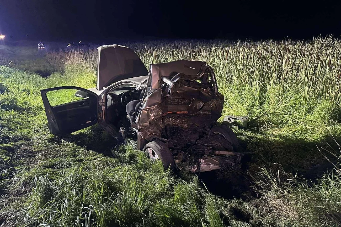 W wypadku drogowym między Bisztynkiem a Wozławkami zginął strażak i jego 2-letni syn. Wrak samochodu na trawie przy drodze. Tył auta jest kompletnie zmiażdżony.