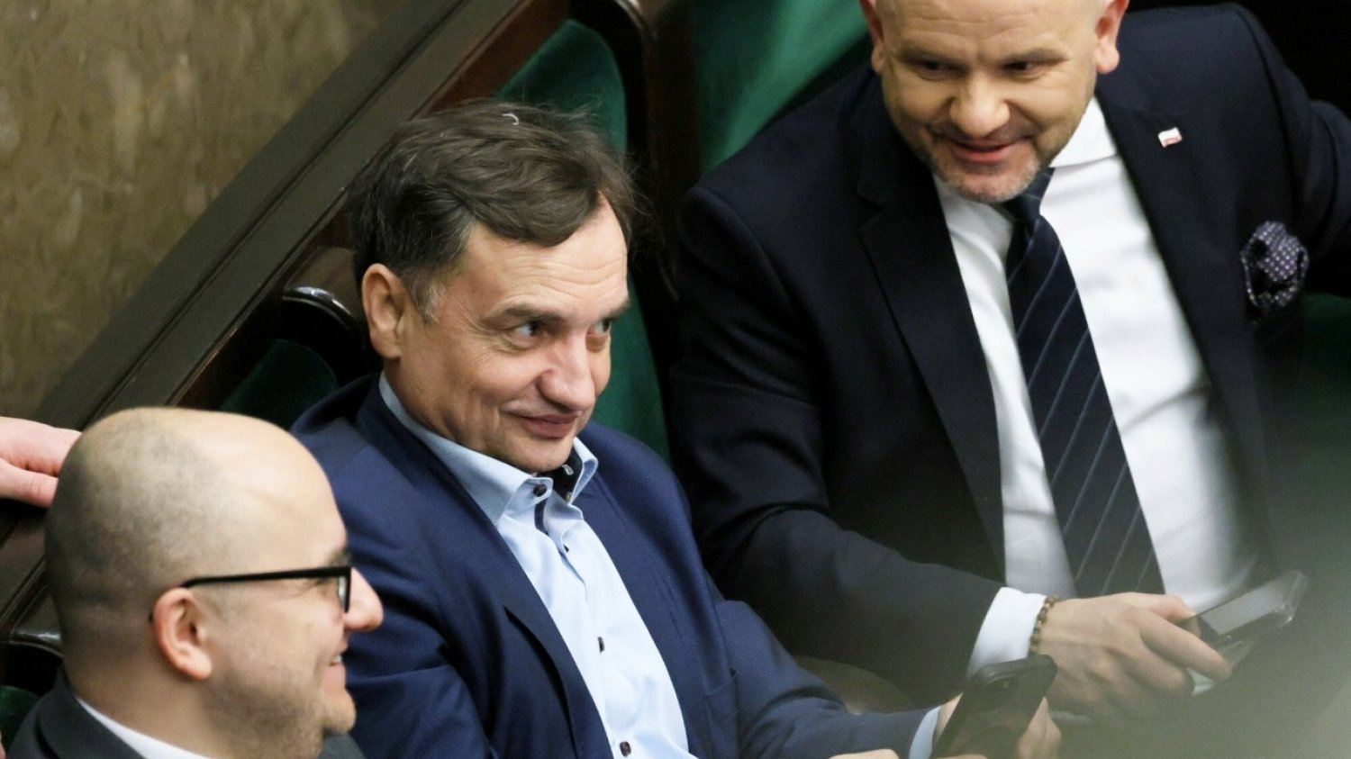 Poseł Zbigniew Ziobro siedzący na sali obrad w Sejmie w otoczeniu posłów Dariusza Mateckiego i Mariusza Goska.