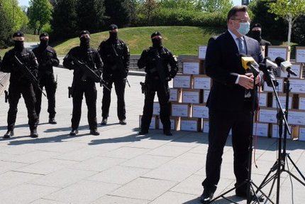 Wiceminister sprawiedliwości Michał Wójcik przekazał górnikom maseczki na tle ludzi uzbrojonych w karabiny.