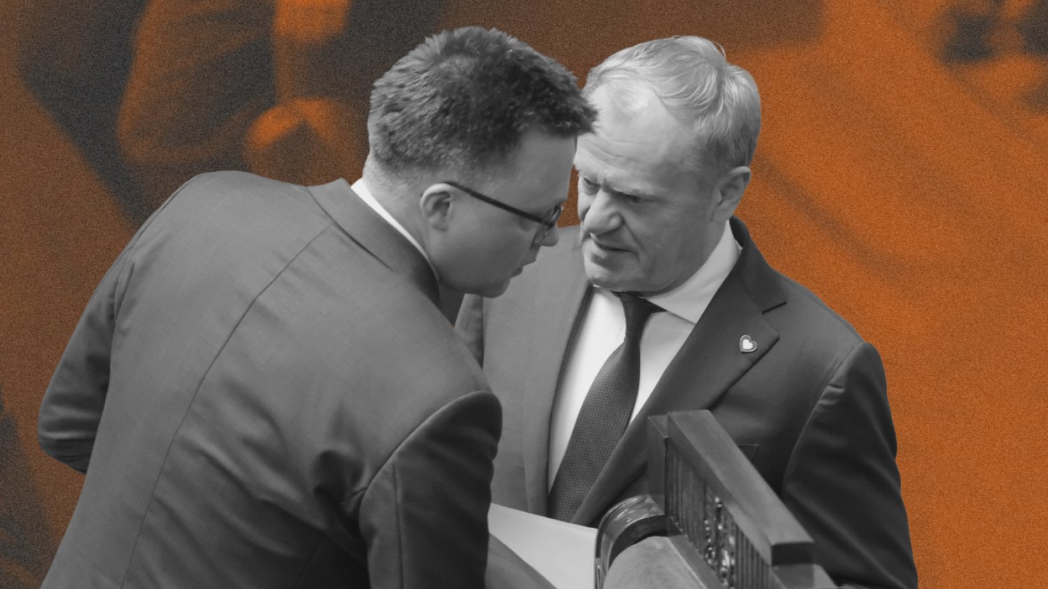 Szymon Hołownia i Donald Tusk w Sejmie. Rozmawiają na stojąco na sali obrad. Donald Tusk ma w ręku papiery, Hołownia przechyla głowę w jego kierunku.
