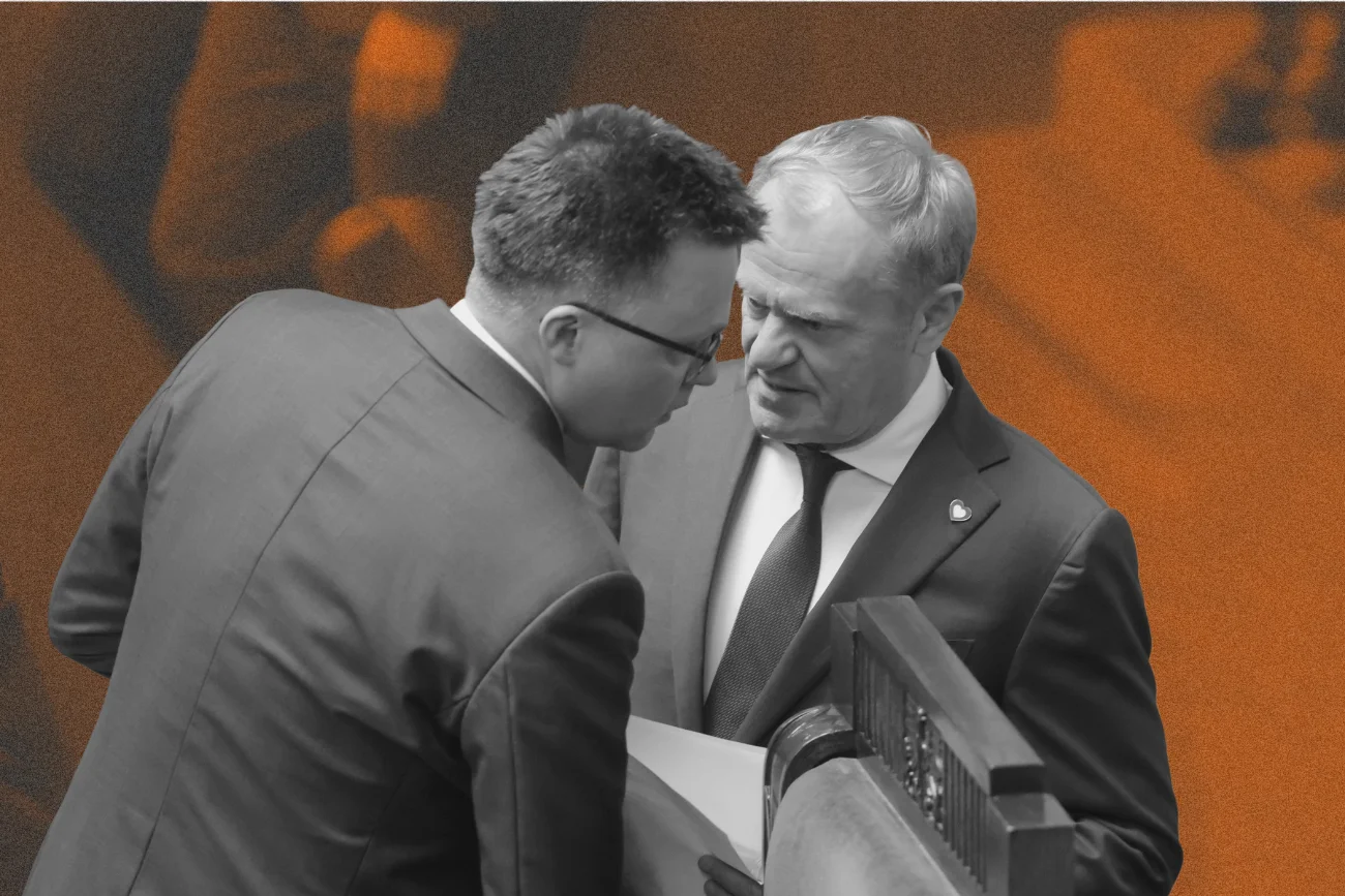 Szymon Hołownia i Donald Tusk w Sejmie. Rozmawiają na stojąco na sali obrad. Donald Tusk ma w ręku papiery, Hołownia przechyla głowę w jego kierunku.