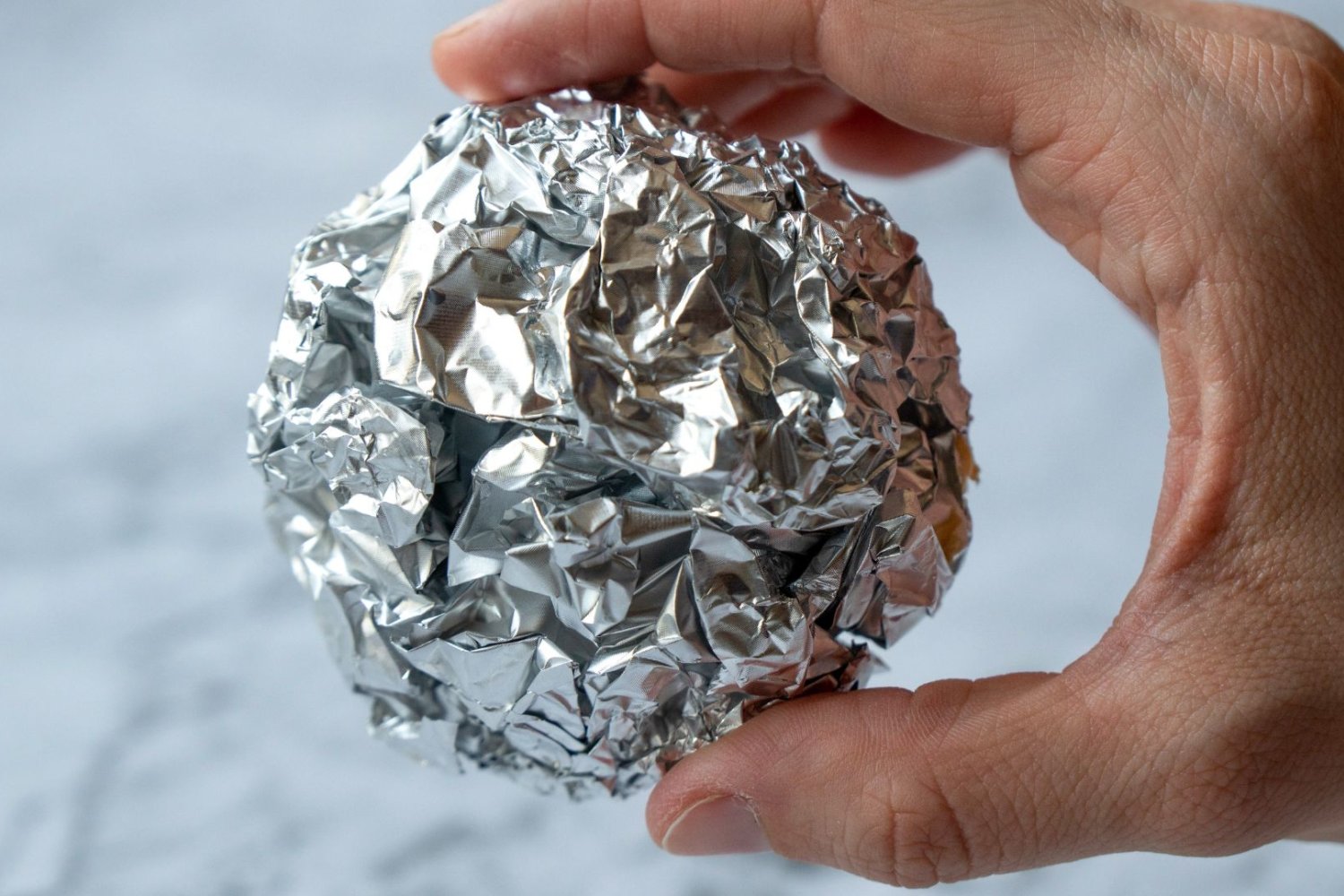 Zwiń folię aluminiową w kulkę i wrzuć do blendera. Po minucie mi podziękujesz Osoba trzymająca w dłoni kulkę z folii aluminiowej.