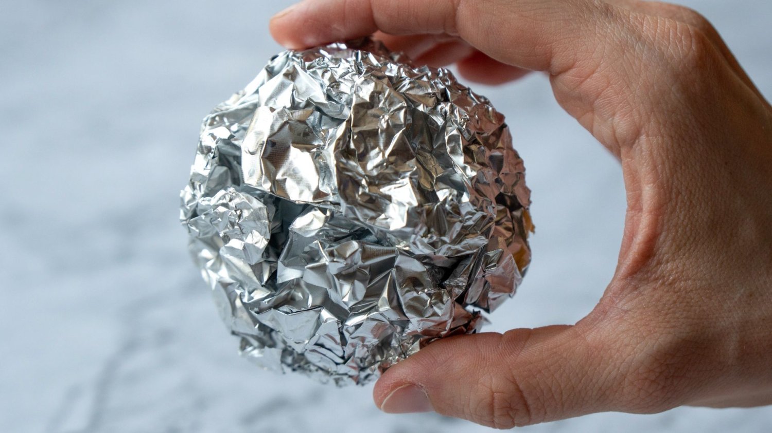 Zwiń folię aluminiową w kulkę i wrzuć do blendera. Po minucie mi podziękujesz Osoba trzymająca w dłoni kulkę z folii aluminiowej.