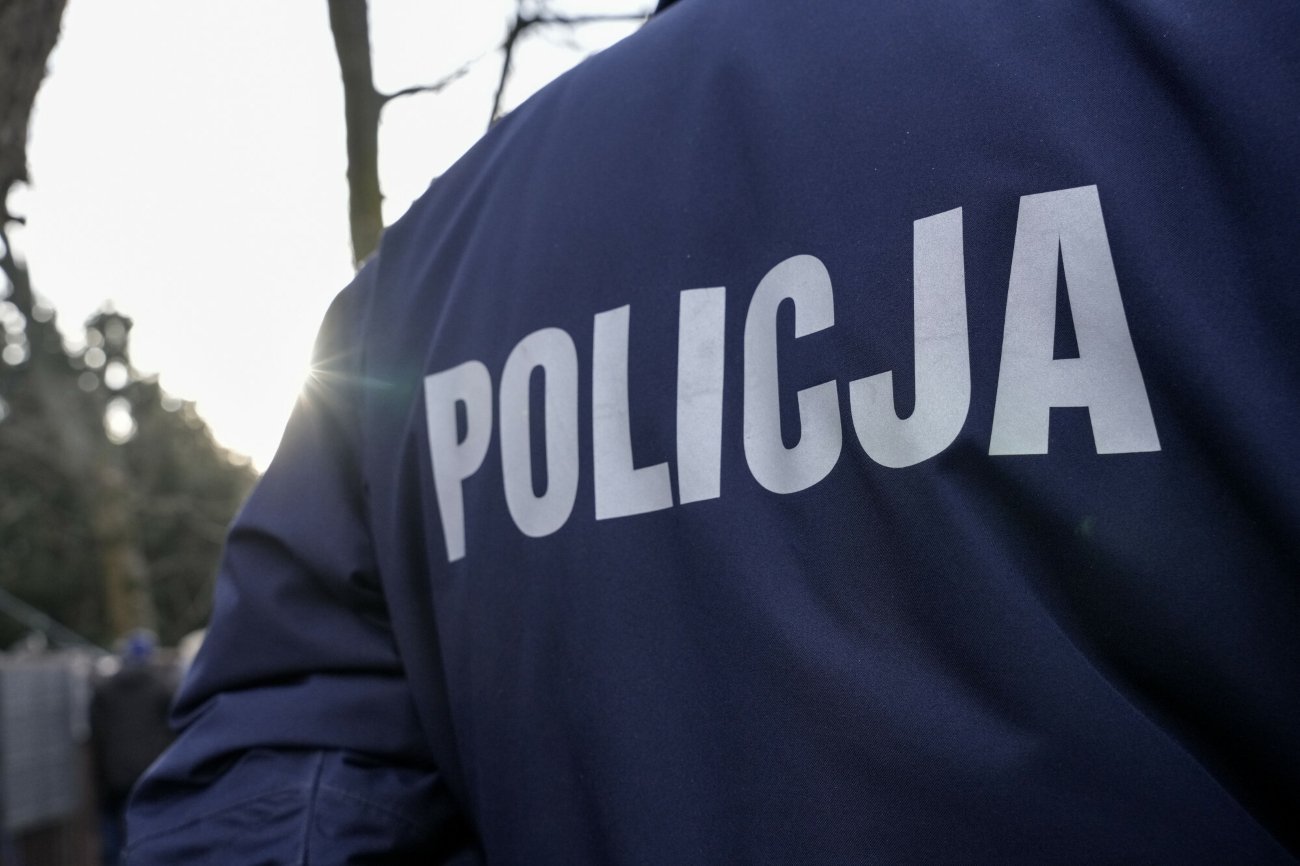 Plecy funkcjonariusza w mundurze z napisem "Policja".