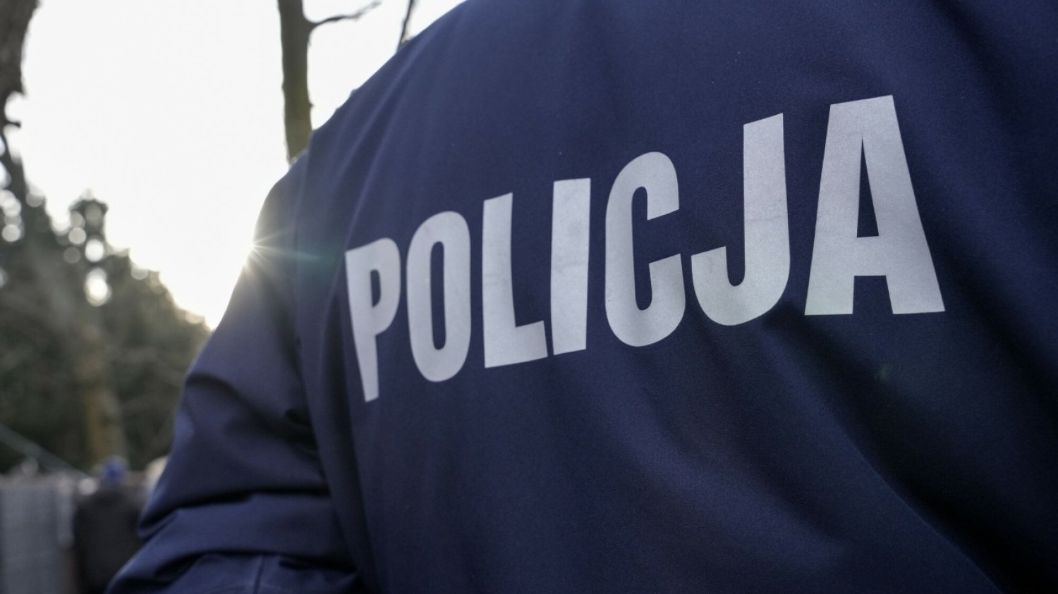 Plecy funkcjonariusza w mundurze z napisem "Policja".