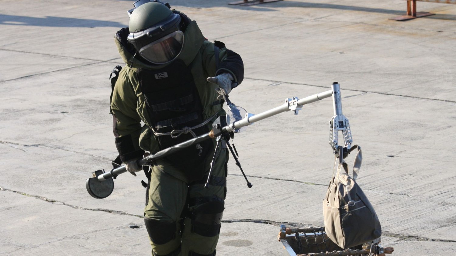 Alarmy w szkołach w całym kraju. Co na to policja? Odpowiedź słyszymy lakoniczną Człowiek w kombinezonie ochronnym do usuwania bomb i kasku podnoszący plecak.