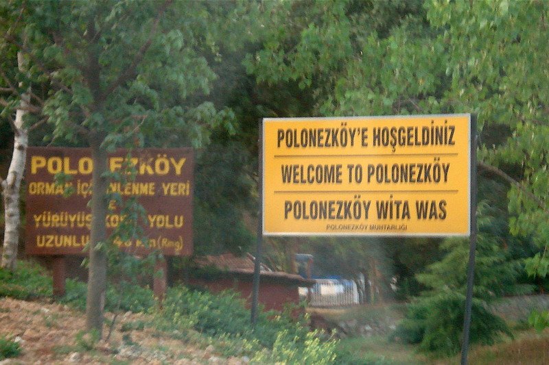 Tablica w trzech językach witająca wszystkich, którzy odwiedzają Adampol.