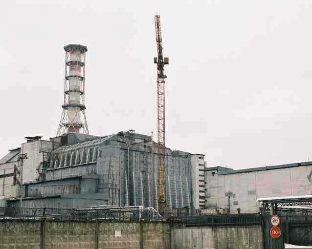 Współczesny widok elektrowni w Czarnobylu. Zniszczony reaktor został osłonięty żelbetową konstrukcją zwaną sarkofagiem, która zapobiega dalszym uwolnieniom substancji promieniotwórczych oraz zatrzymuje emitowane z pozostałości reaktora promieniowanie.