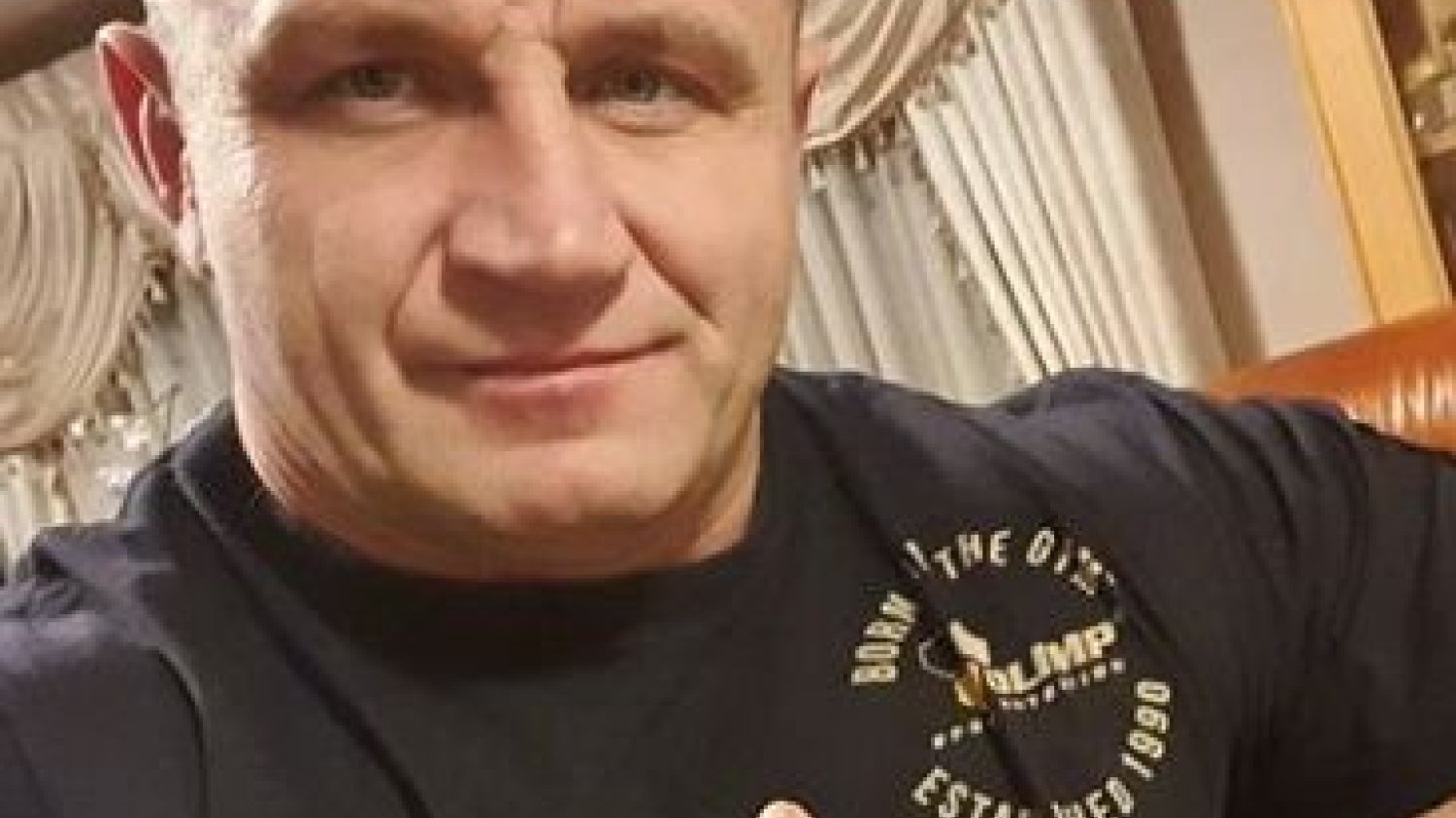 Mariusz Pudzianowski na tle suplementu diety z witaminą C, który poleca go do ochrony przed koronawirusem.