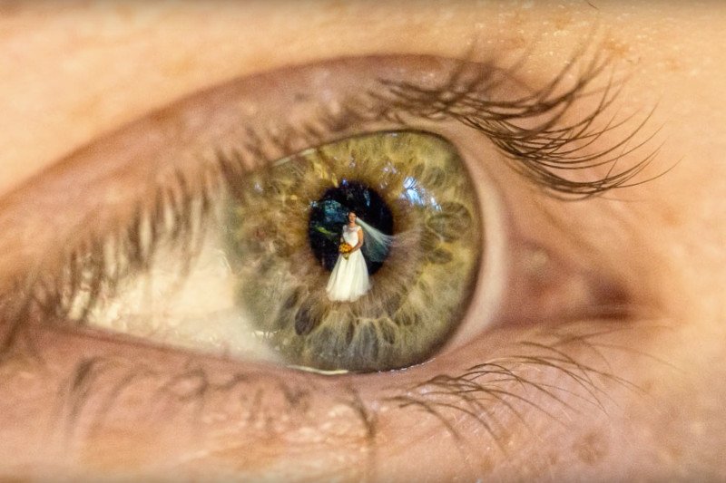 Niekonwencjonalny pomysł na fotografię ślubną? Odbicie młodej pary w oczach gości.