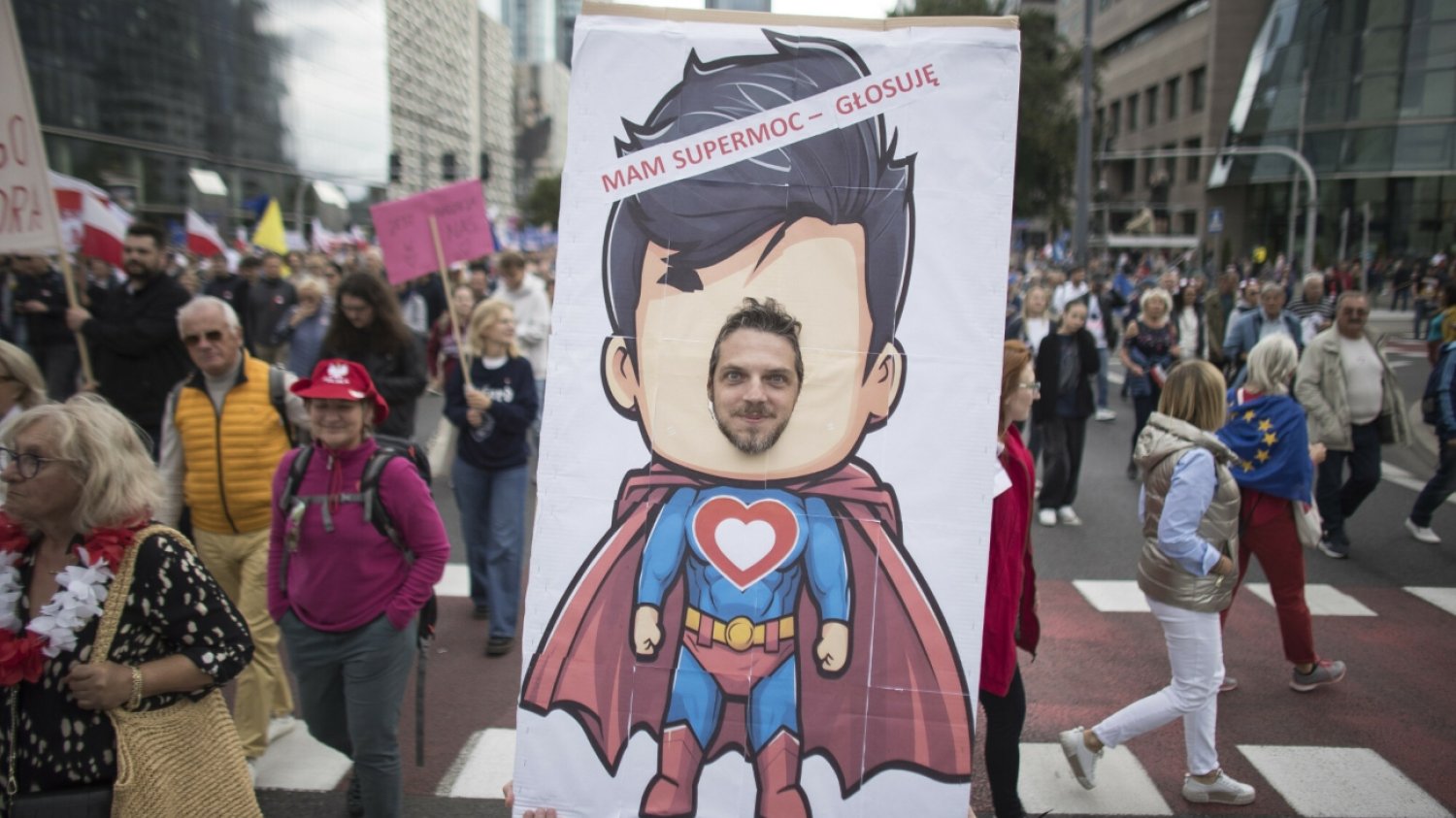 Mężczyzna pozujący do zdjęcia jako suberbohater. Nad nim napis: mam supermoc - głosuję.