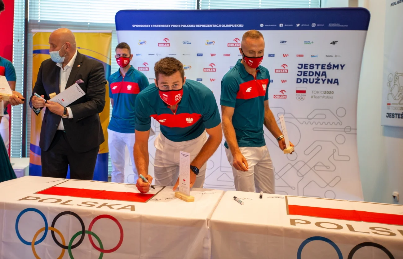 Michał Kubiak składa podpis na polskiej fladze po ślubowaniu olimpijskim