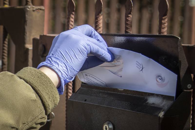 Listonoszka roznosi pocztę w maseczce ochronnej i jednorazowych rękawiczkach