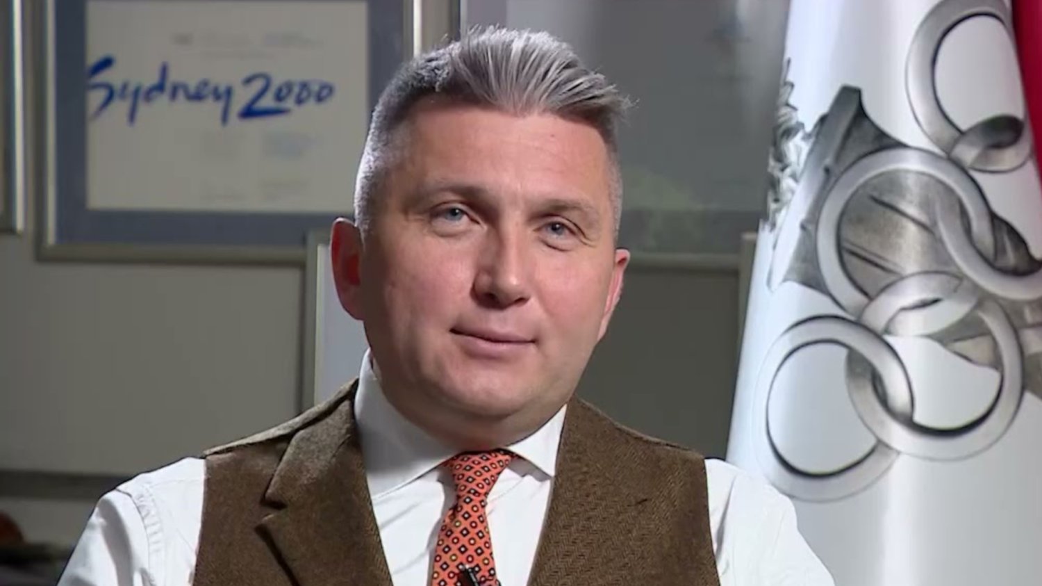Prezes PKOl Radosław Piesiewicz przemawia na tle flagi olimpijskiej