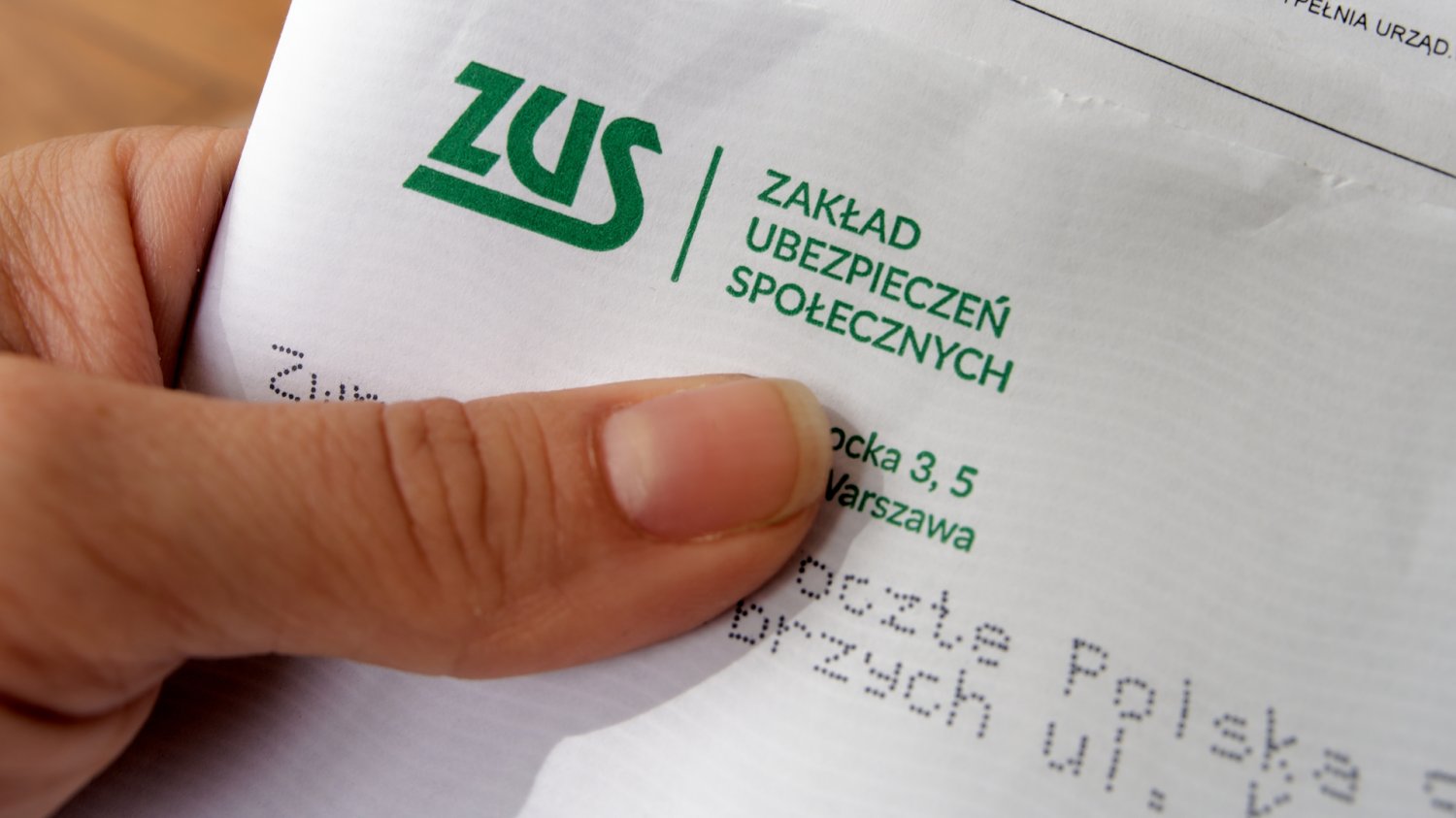 Listy z ZUS 13 emerytura zwrot decyzje 2026 Kobieta odbierająca oficjalny list z ZUS. Zakład rozsyła listy, w których znajdują się dwie decyzje oraz ewentualne pouczenie o zwrocie 13. emerytury.