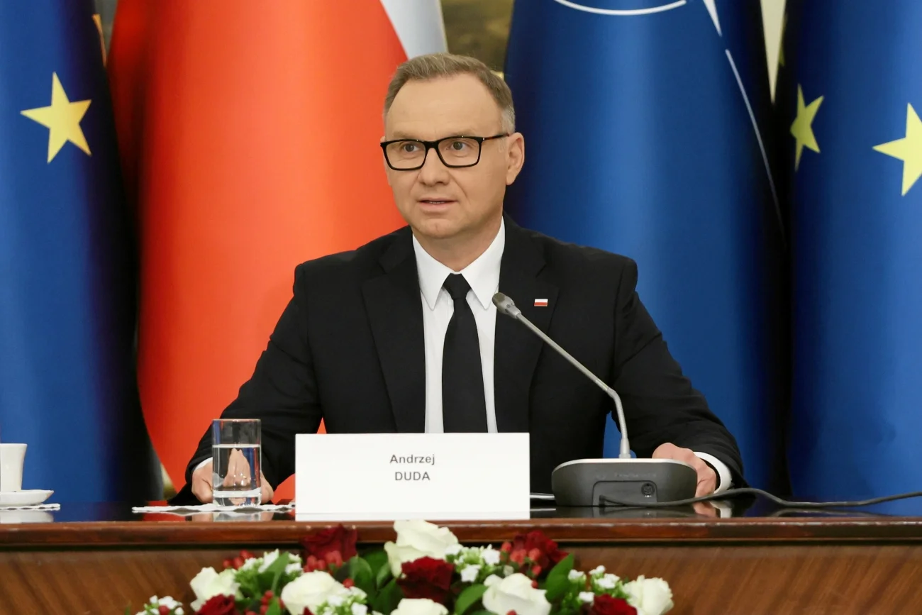Andrzej Duda na posiedzeniu RBN. Prezydent Andrzej Duda siedzący przy stole na tle flagi Polski i Unii Europejskiej. Spotkanie Rady Bezpieczeństwa Narodowego.