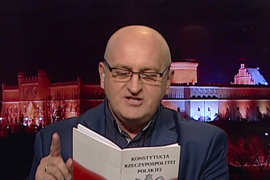 Marian Kowalski w robi zagorzałego czytelnika Konstytucji RP.