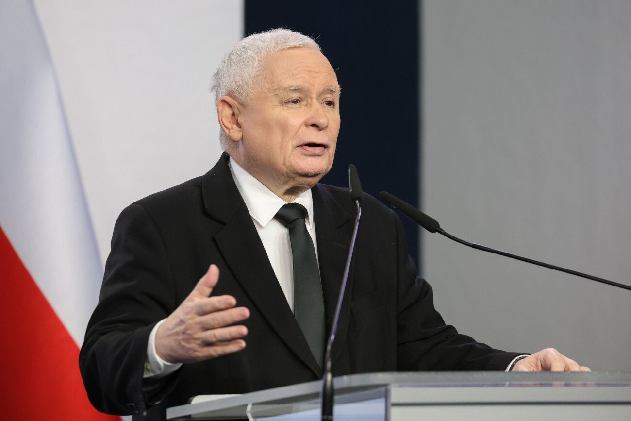 Prezes PiS Jarosław Kaczyński stojący za pulpitem podczas konferencji prasowej.