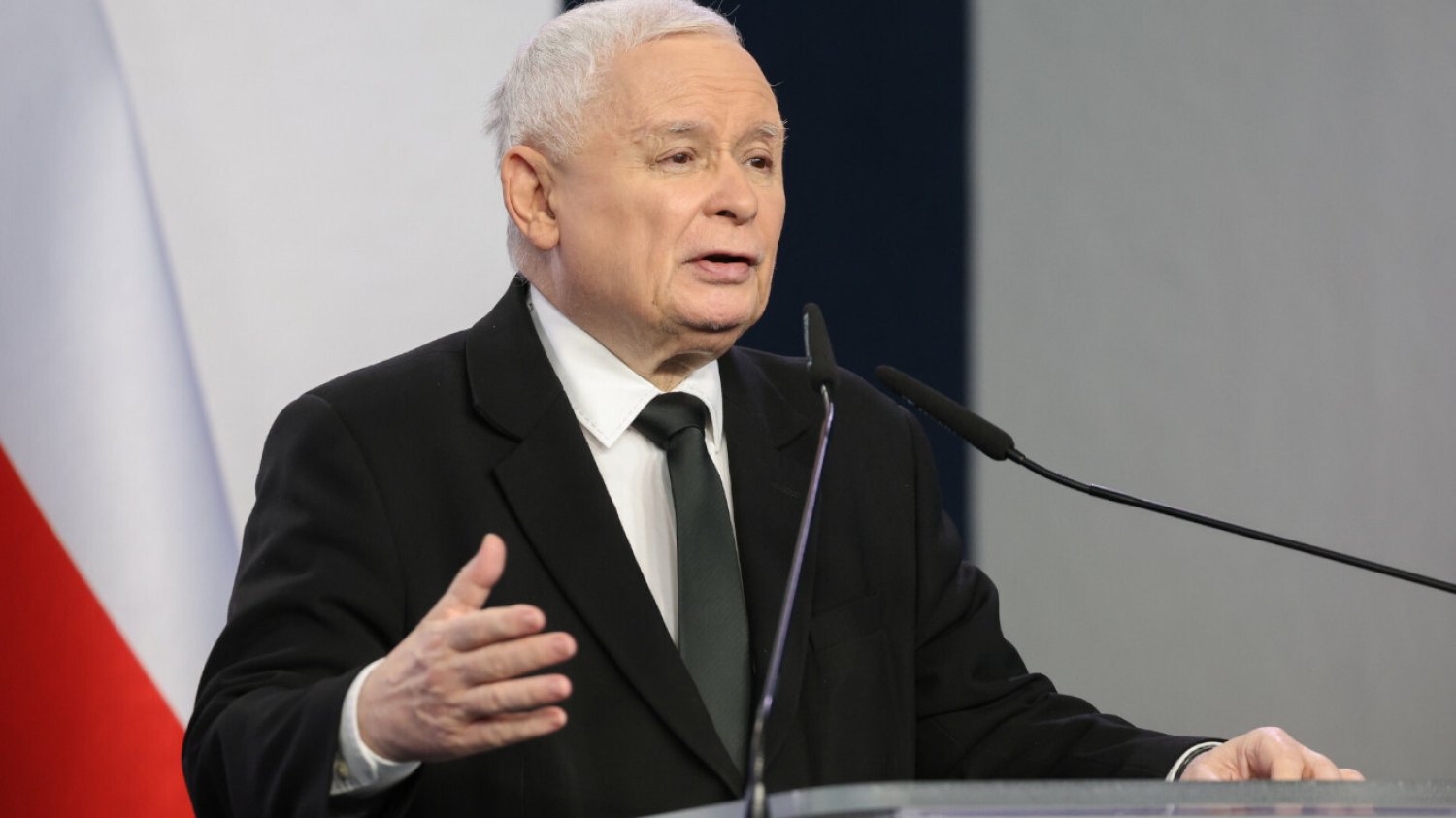 Prezes PiS Jarosław Kaczyński stojący za pulpitem podczas konferencji prasowej.