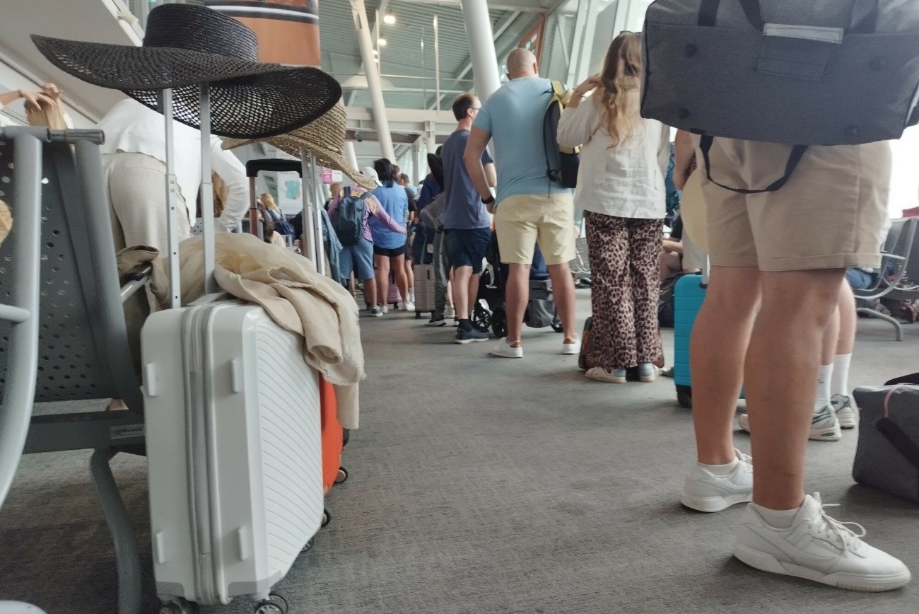 Walizki, kapelusze przeciwsłoneczne i podróżni czekający na lotnisku.