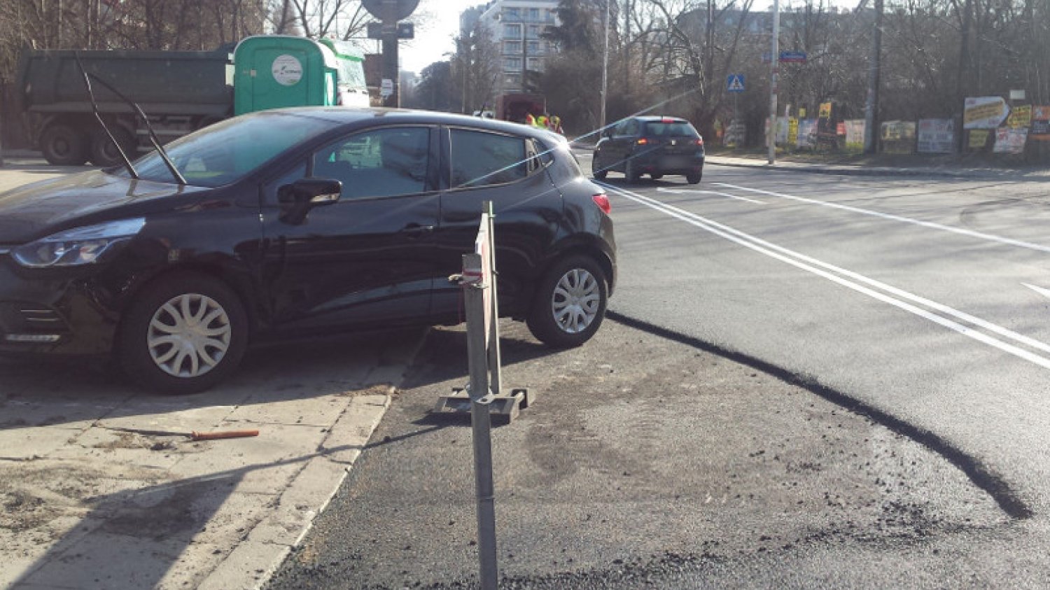 Drogowcy nowy asfalt kładli dookoła źle zaparkowanych samochodów.