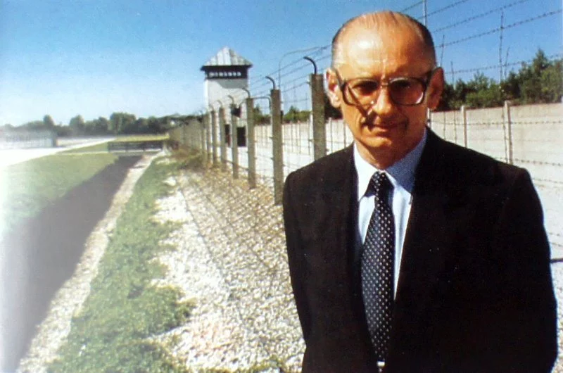 Władysław Bartoszewski po wojnie na tle byłego niemieckiego obozu.