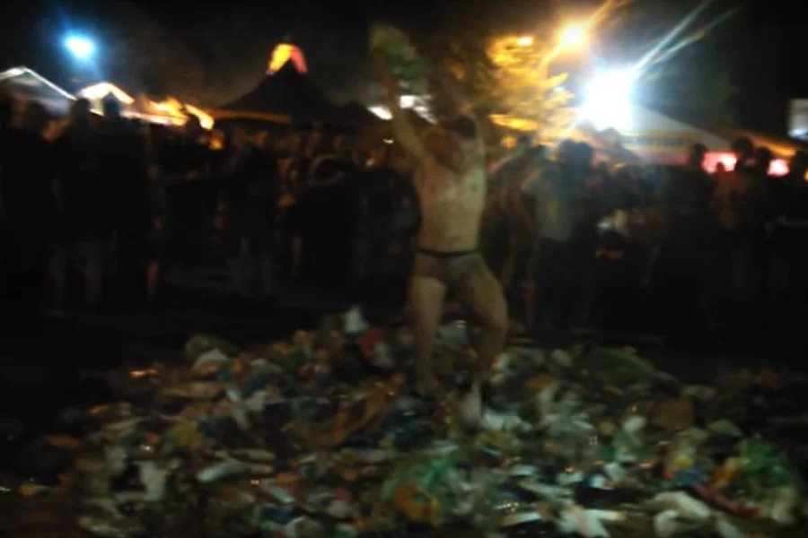 Mężczyzna tarza się w stercie śmieci jak w transie w rytm festiwalowej muzyki.