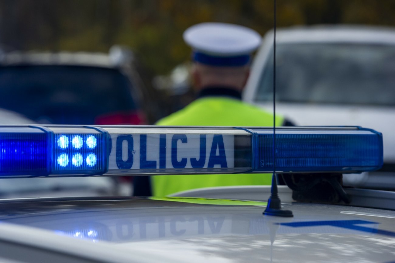 Radiowóz i stojący przed nim policjant. Zdjęcie ilustracyjne.