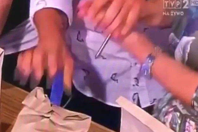 Na klatce filmu widać, że czubek gwoździa jest daleko od dłoni dziennikarki.