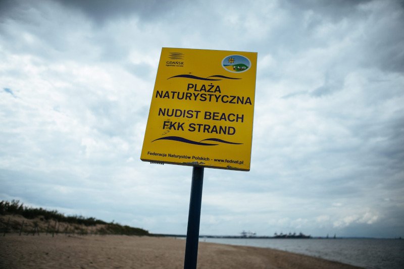 Nudyści, nieświadomi granic plaży dla naturystów, opalają się w strefie dla okrytych plażowiczów.