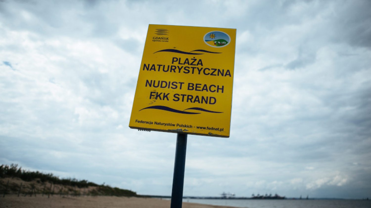 Nudyści, nieświadomi granic plaży dla naturystów, opalają się w strefie dla okrytych plażowiczów.