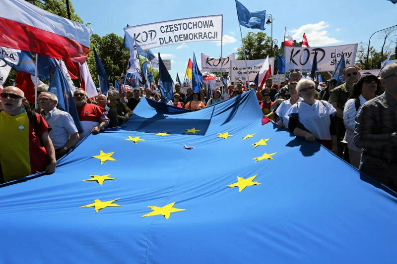 Uczestnicy marszu KOD i opozycji z flagą UE.
