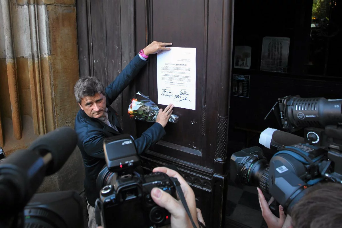 Tak, pozując dla fotoreporterów, Janusz Palikot przyklejał do drzwi kościoła swój akt apostazji.