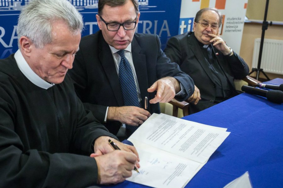 Zdzisław Klafka z toruńskiej uczelni i Jan Szarek z IPN  podpisują porozumienie o współpracy. Wszystkiemu przygląda się ojciec Tadeusz Rydzyk.