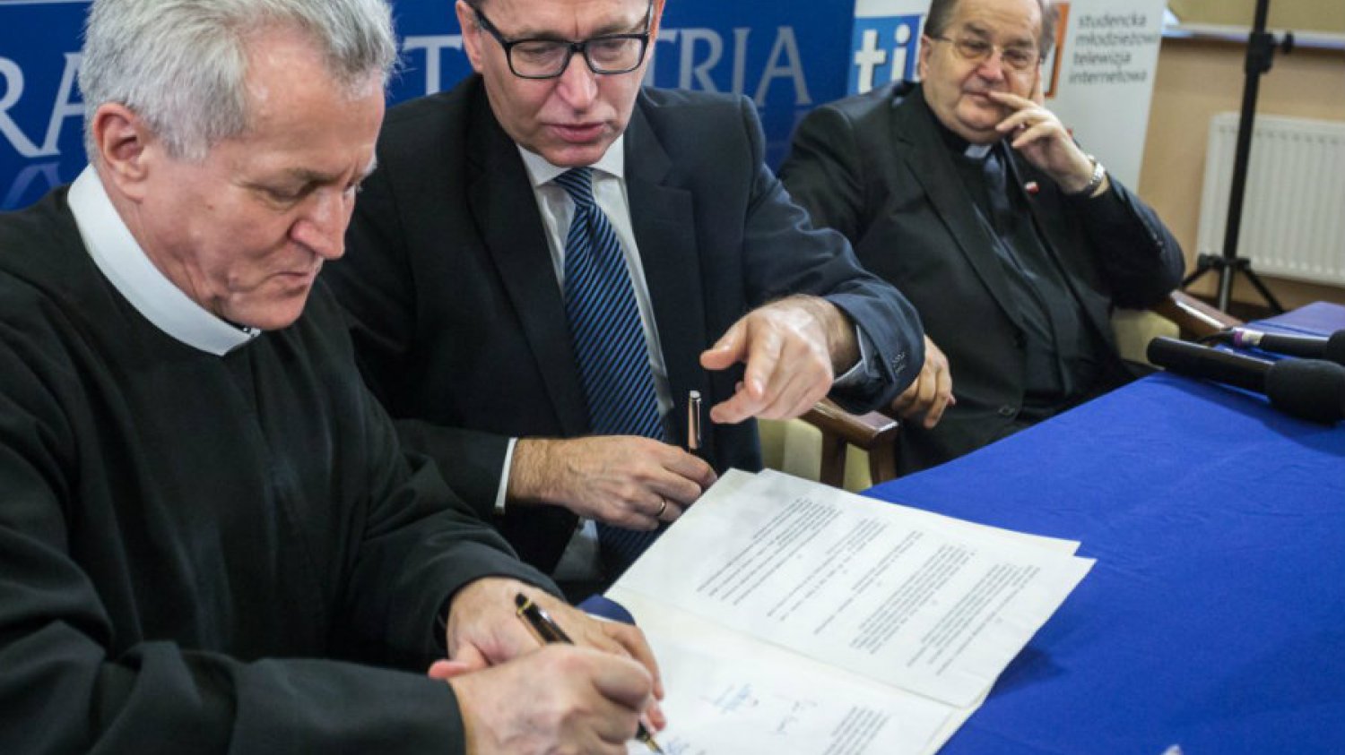 Zdzisław Klafka z toruńskiej uczelni i Jan Szarek z IPN  podpisują porozumienie o współpracy. Wszystkiemu przygląda się ojciec Tadeusz Rydzyk.